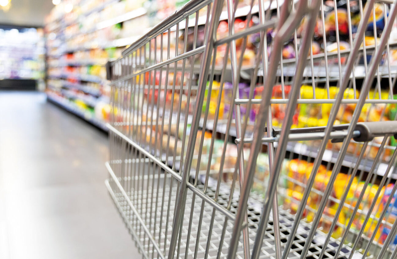 Shopping trolley cart against supermarket aisle blurred backgrou